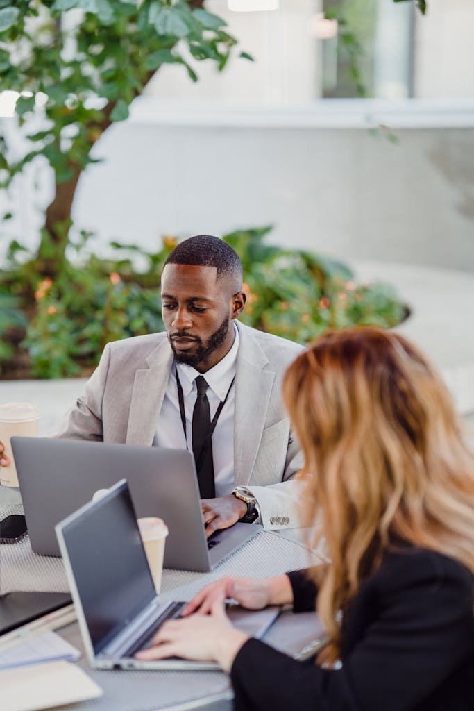 Business professionals working together on laptops at an outdoor table.