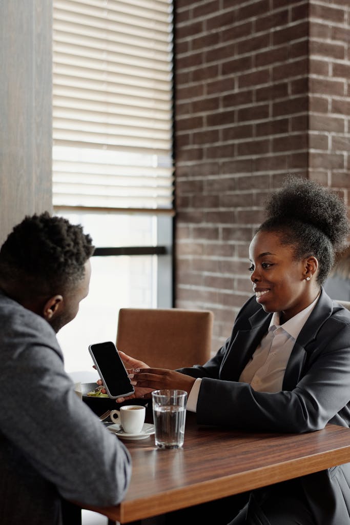 Two professionals discussing business over coffee in a cafe setting.